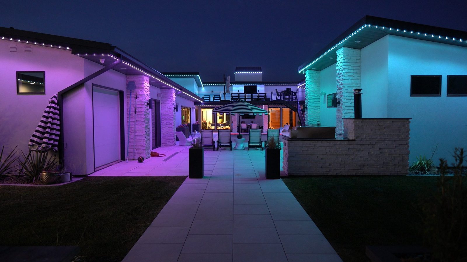 A backyard pool and patio lit in warm white